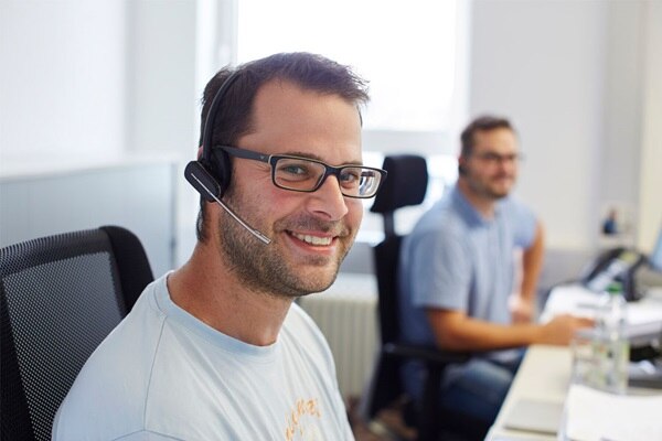 Klantenservice medewerker met headset en een collega op de achtergrond