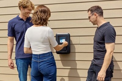 vrouw houdt kaart voor laadpaal, 2 mannen kijken