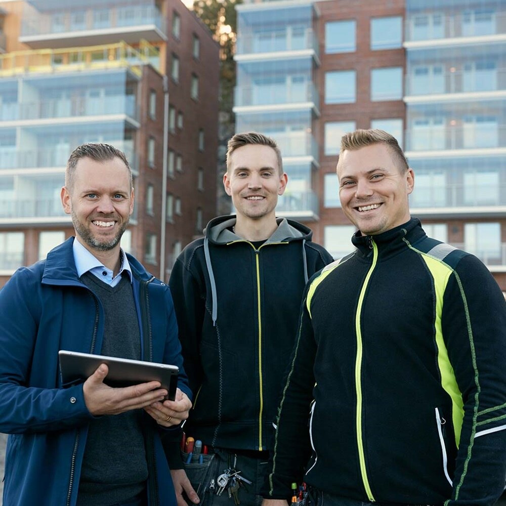 3 mannen die voor appartementsgebouw staan