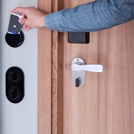 Hotelgast die kaart tegen kaartlezer van Hager houdt om de deur te openen