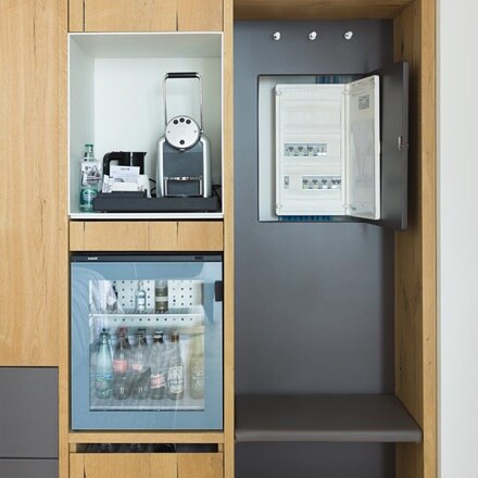 Minibar en koffieautomaat in kast met open elektriciteitskast van Hager ernaast