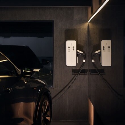 elektrische zwarte auto laadt op aan een laadpaal in een donkere garage