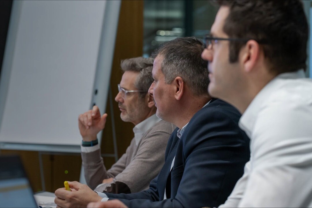 3 personen die een opleiding volgen. Er staat een flipchart achteraan.
