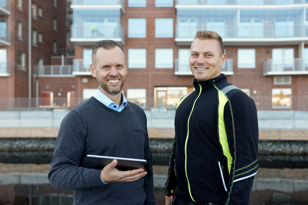 Twee professionals buiten een gebouw met een die een digitale tablet vasthoudt