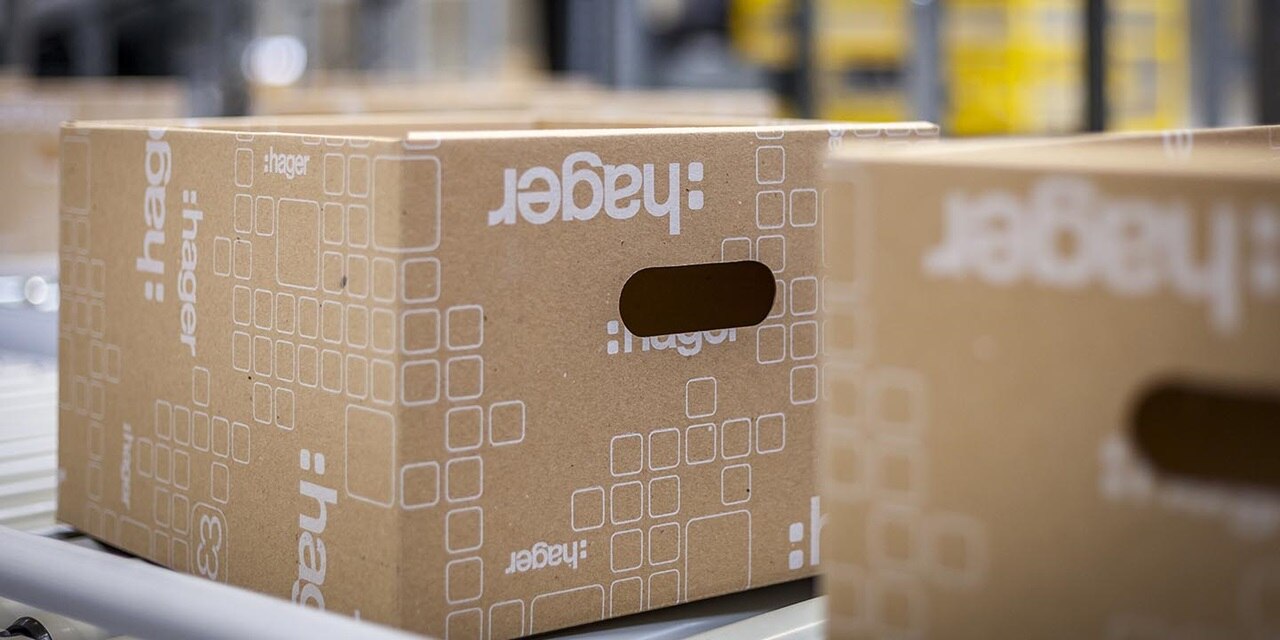 Kartonnen dozen met het merk “hager” op een lopende band in een magazijn of logistieke omgeving.