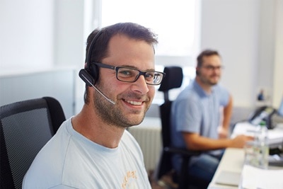 Klantenservice medewerker met headset en een collega op de achtergrond