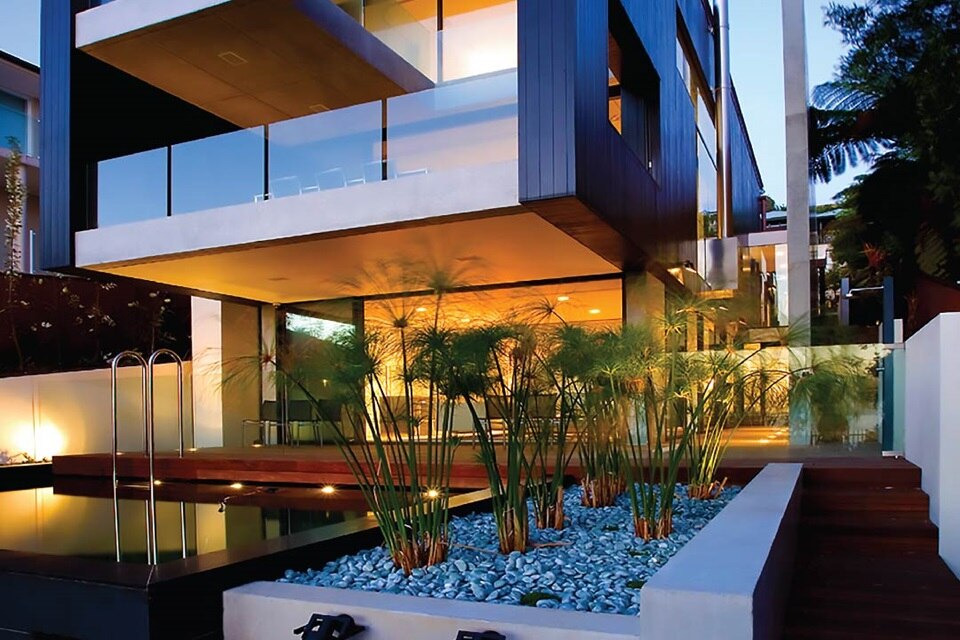 Modern house exterior at dusk with outdoor lighting and reflection on water features