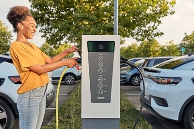 Osoba korzystająca ze stacji ładowania pojazdów elektrycznych Hager na parkingu