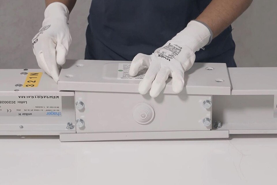 Technik w rękawiczkach montujący modułową obudowę elektryczną