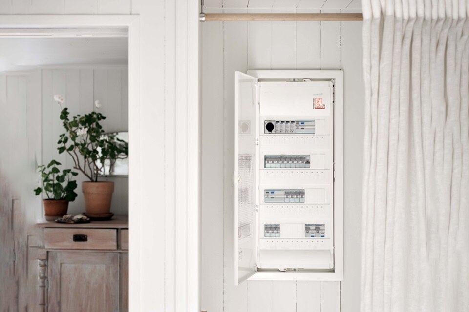 Otwarta rozdzielnica elektryczna z wyłącznikami obwodów w jasnym wnętrzu mieszkalnym
