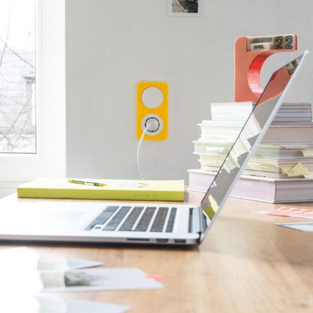 Laptop leżący na biurku w nowoczesnym domu, podłączony do ładowania do gniazdka Berker