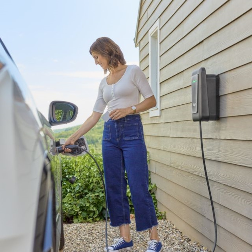 kobieta ladujaca samochod elektryczny za pomoca stacji witty one firmy Hager