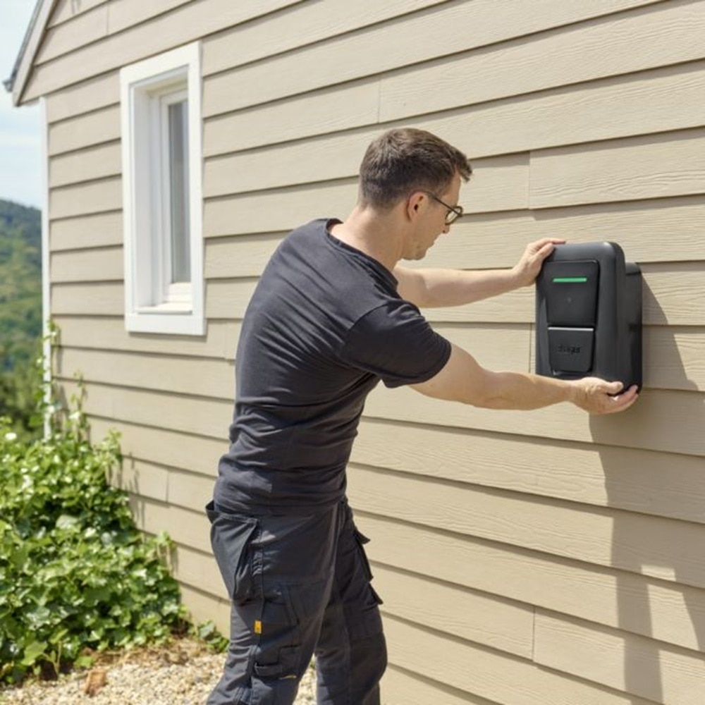 Mężczyzna wykonujący montaż stacji witty one na ścianie domu