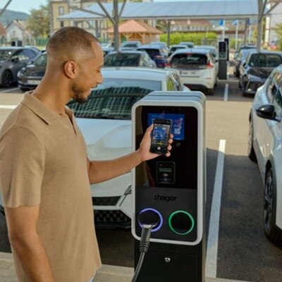 Mężczyzna dokonujący płatności zbliżeniowej telefonem za ładowanie pojazdu elektrycznego przy pomocy stacji ładowania witty park 2