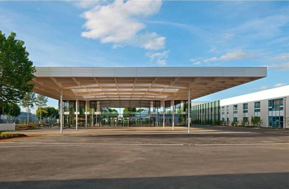 Fachada de edifício comercial moderno com área de estacionamento ampla e cobertura