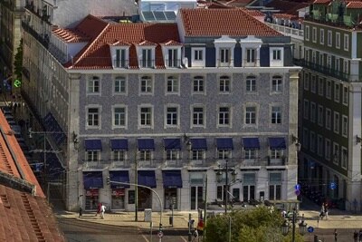 Vista de edifícios tradicionais com azulejos em Lisboa, com telhados vermelhos e pedestres na rua