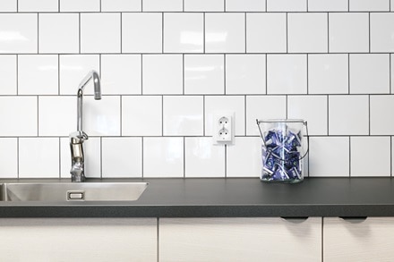 Vägguttag och strömbrytare Berker S.1 från Hager monterar mot vit klinker i kök i kontorshus Aptiv i Göteborg