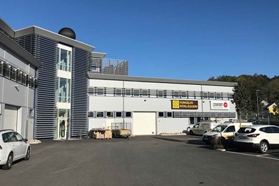 Yttre av industribyggnad med parkeringsplats och skyltning