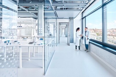 Modernt laboratorieinteriör med två yrkespersoner som diskuterar, utrustat med elektriska datapunkter och belysningssystem