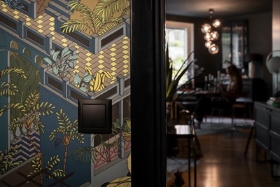 Modernt interiör med dekorativ vägg och stilren svart ljusströmbrytare med en suddig bakgrund av en person som sitter vid ett bord