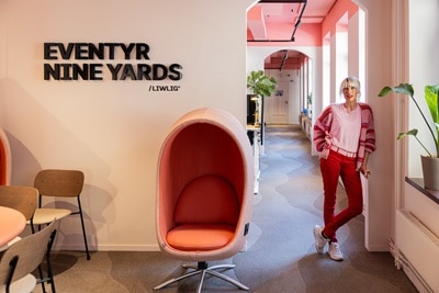 Person står i en modern kontorskorridor med stilren inredning och en poddstol