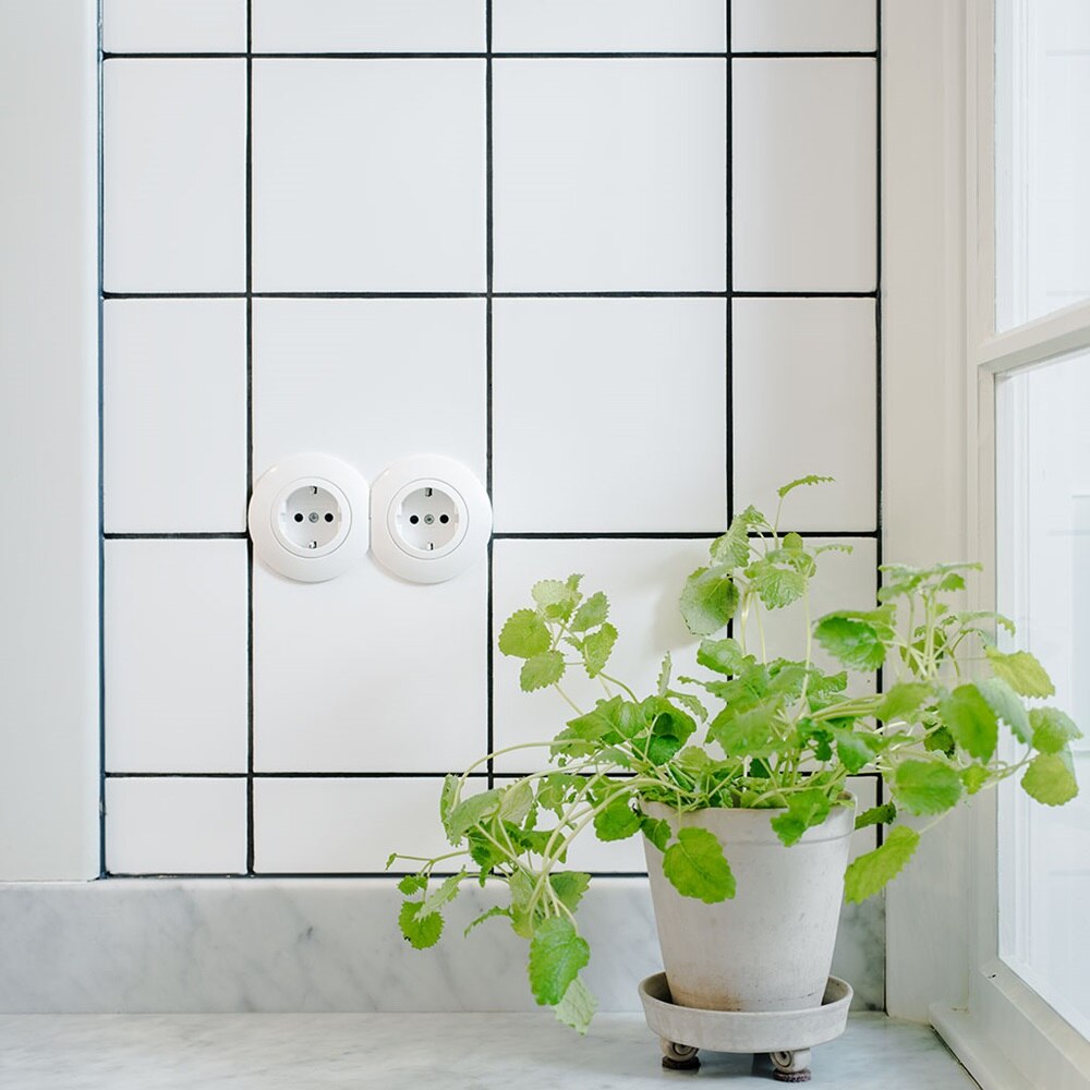 Vägguttag Serie berker 1930 i vitt från Hager  monterad mot klinker