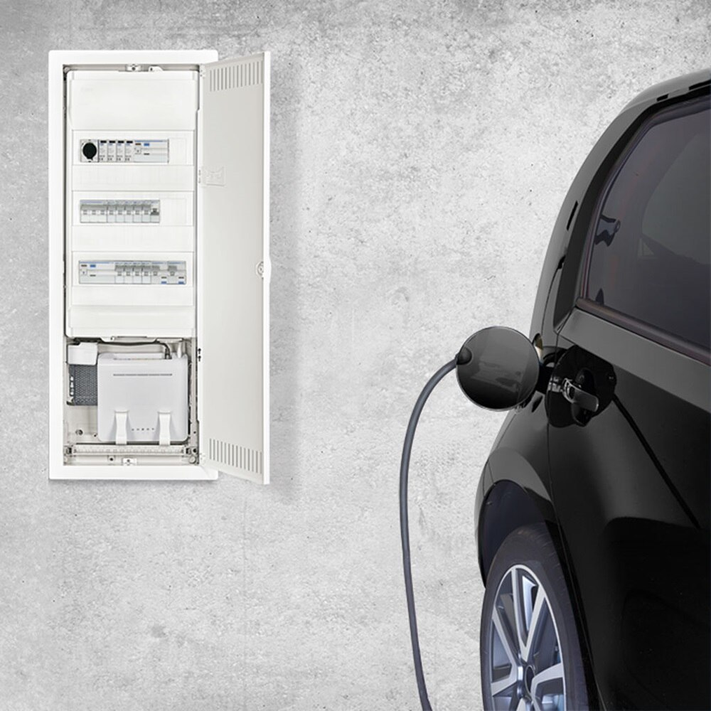 Elbil ansluten till  en laddbox bredvid en öppen elcentral på en betongvägg