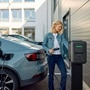 Kvinna som laddar sin bil med smarta laddboxen witty pro från Hager på en privat parkeringsplats