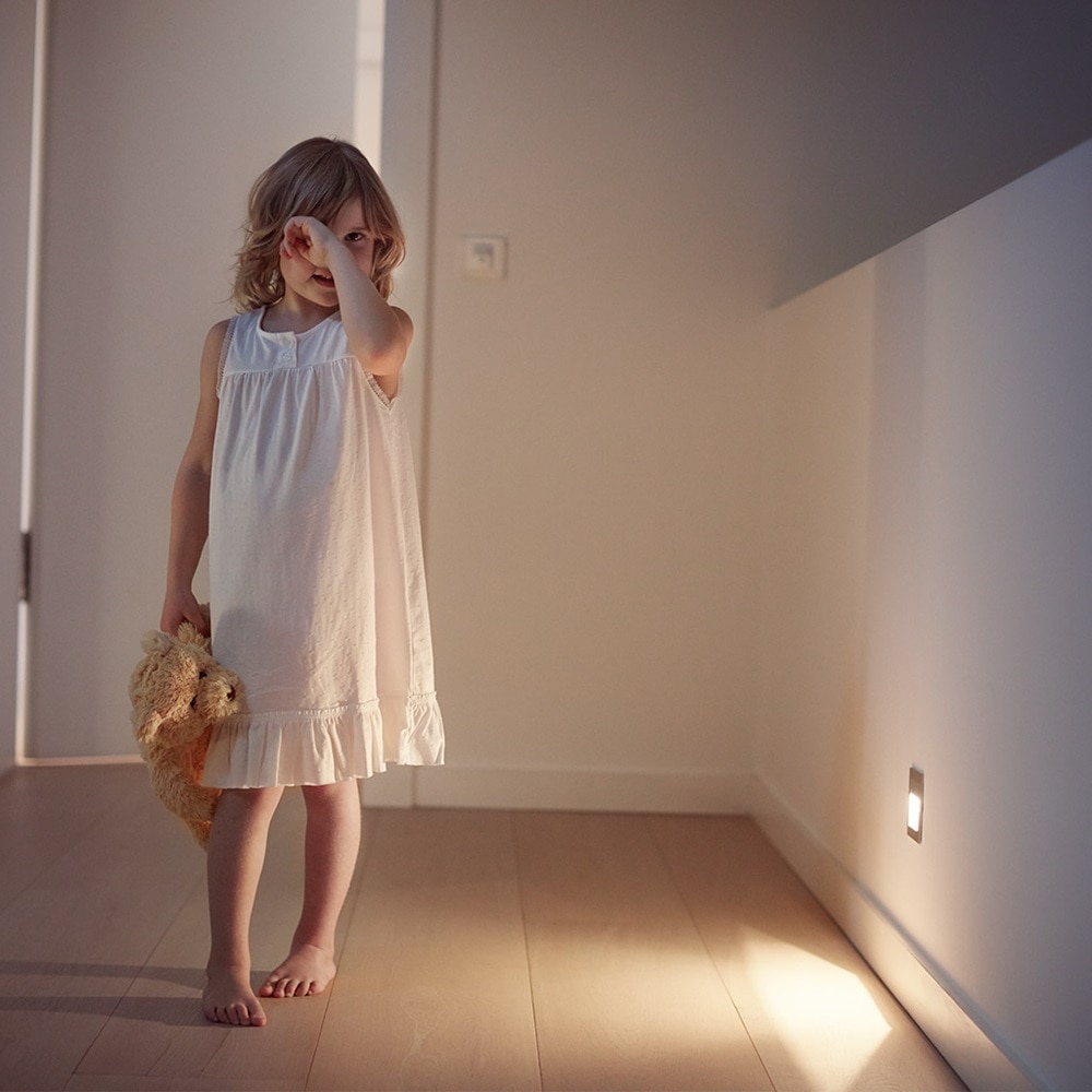 Exempel på väggmontering av Hager Q.7 strömställarserie med downlight och barn i mörker