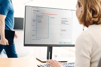 Person som väljer alternativ i Hager konfigurationsprogramvara på en datorskärm med en annan individ i bakgrunden