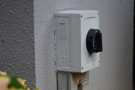 Hager outdoor socket on a gray wall.4
